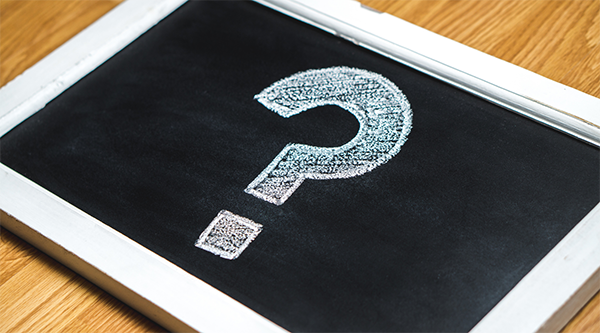 Question mark drawn in white chalk on a rectangular chalkboard with a white frame.