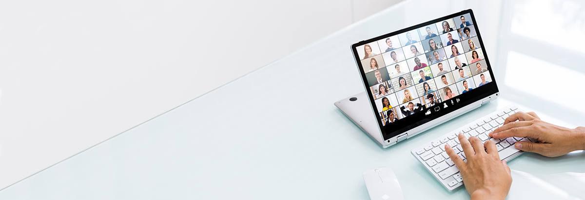 white background laptop on white table with a screen showing a grid with multiple people - similar to a large online team meeting