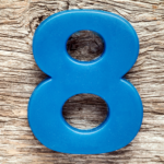 Blue plastic number 8 on a light wood background