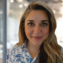 Woman with light brown hair and brown eyes in a white and blue patterned shirt.