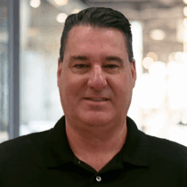 Caucasian man with short dark hair and a black polo shirt