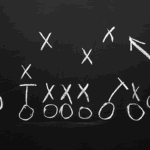 A gameplan with Xs and Os in white chalk on a black chalkboard